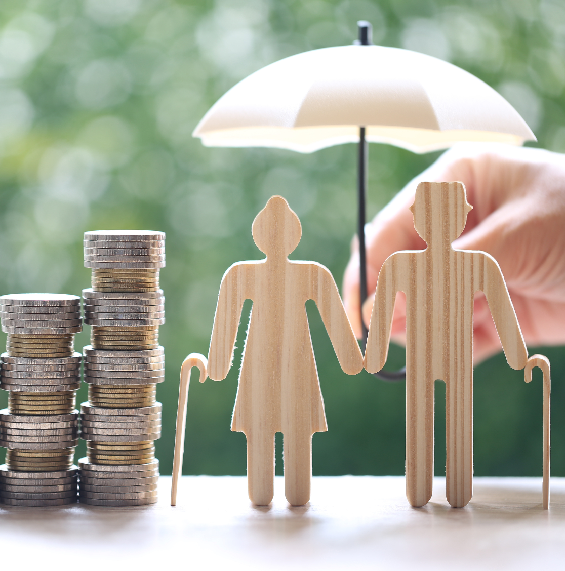 Wooden figures holding hands next to a stack of coins